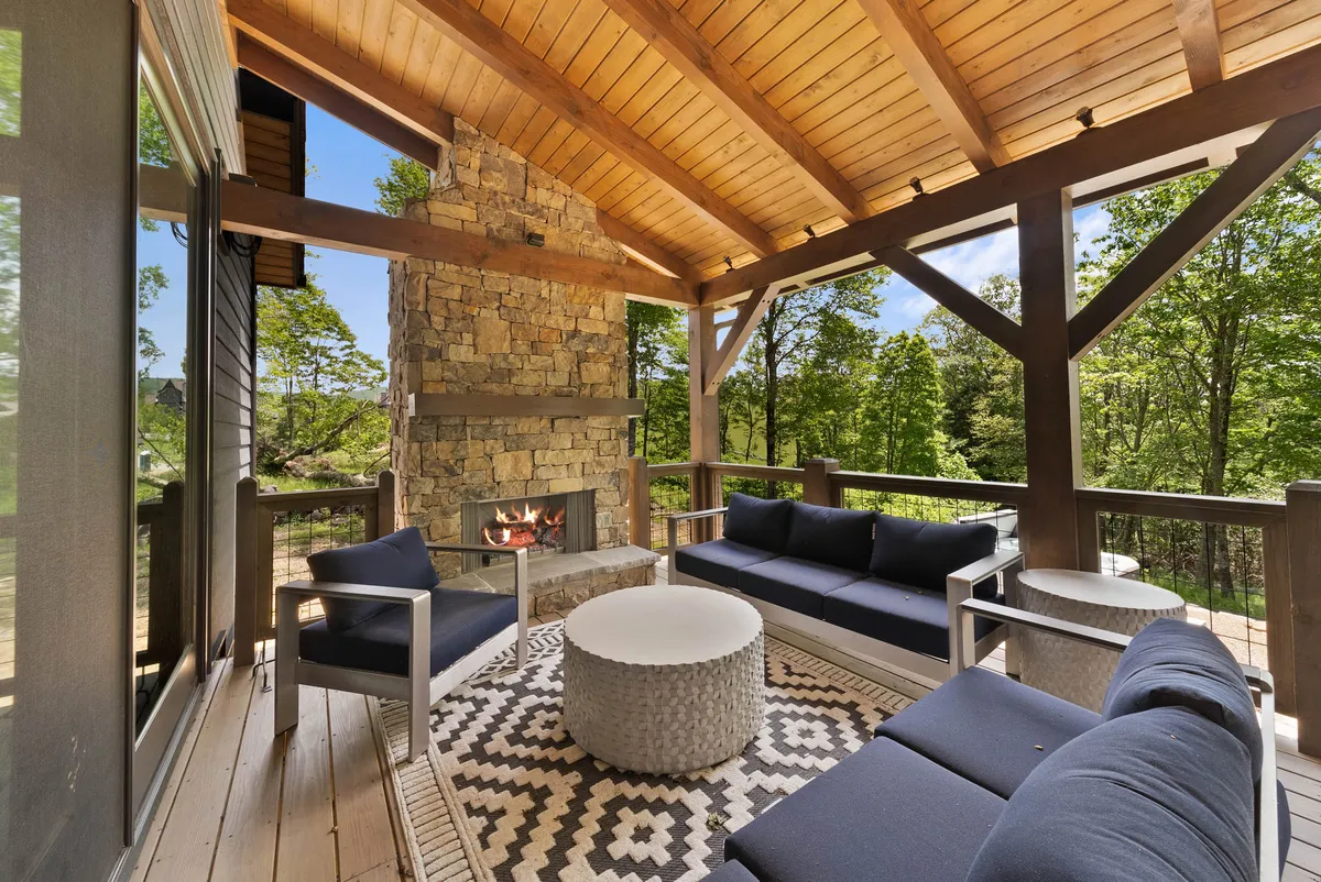 An inviting outdoor living area with a stone fireplace, comfortable seating, and a decorative rug. The setup is ideal for socializing, entertaining, and enjoying nature, encapsulating the warmth of community gatherings.
